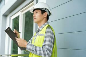 el inspector o ingeniero está inspeccionando la construcción y el aseguramiento de la calidad de la nueva casa usando una lista de verificación. ingenieros o arquitectos o contratistas trabajan para construir la casa antes de entregársela al propietario foto