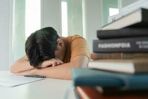 el estudiante asiático tiene ansiedad debido a los exámenes, los hombres se preparan para el examen y aprenden lecciones en la biblioteca. estrés, desesperación, prisa, malentendido lectura, desanimado, expectativa, conocimiento, cansado foto