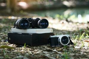 Binoculars, birdwatching guide book Camera and case laying on the ground It is a device for bird watching, animal watching, photographing living things in the forest, and exploring the forest. photo