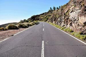 a long empty road with a mountain on one side photo