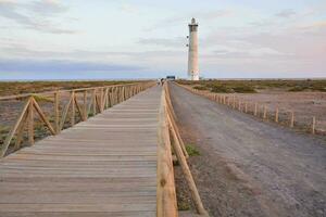 a wooden walkway leads to a lighthouse in the middle of the desert photo