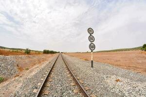 railroad tracks in the desert with a sign photo