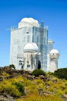 the large white observatory building is surrounded by vegetation photo