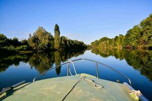 un barco en el río con arboles y un azul cielo foto