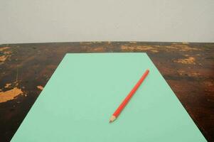 a red pencil on a green sheet of paper photo
