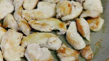 Pieces of chicken breasts frying on a pan with oil close up slow motion full frame background with selective focus and shallow depth of field video