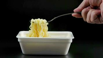 caucasian hand with fork taking, holding and putting back cooked instant noodles video