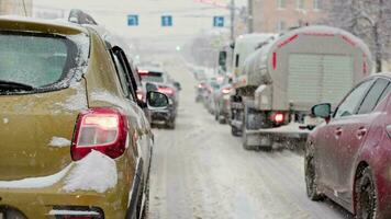 snö täckt bil svans ljus på vinter- dag i trafik stannade på vägkorsning under snöfall video
