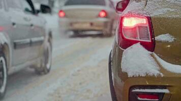 snow covered car tail light at winter day in traffic during snowfall video