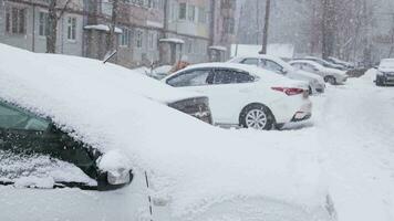 winter daylight blizzard in russian street with parked cars along russian khrushchevka building video