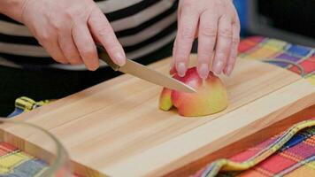 senior vrouw besnoeiing rood appel met een mes Aan houten snijdend bord video