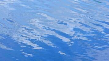 pequeño ondas en el superficie de el lago con un reflexión de el azul cielo y blanco nubes video