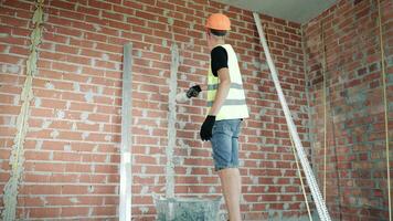 en man plåster en tegel vägg. ett erfaren hantverkare plåster en tegel vägg. video