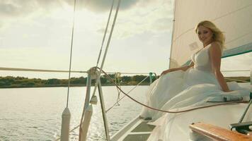 brud på en Yacht på solnedgång. de brudens blick i de distans, de solens strålar video