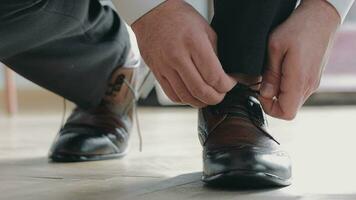 Closeup of men's hands tying shoelaces. Preparation for the wedding day. Groom's morning video