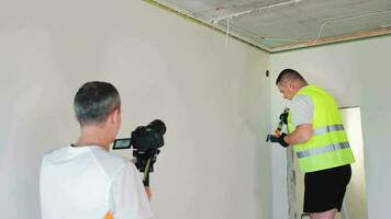 Builder blogger. The video operator is filming the work process of a painter and plasterer. Interior painting works in the room.