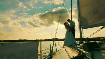 jeunes mariés supporter sur une arc de une voile yacht comme dans titan. jeunes mariés sur une Contexte de magnifique le coucher du soleil video