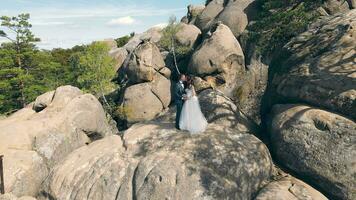 Hochzeit Paar im Berg Felsen von Drohne. Antenne Aussicht glücklich Jungvermählten im Liebe umarmen Stehen auf oben von das Berg. video