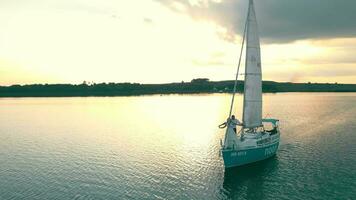 Antenne Aussicht auf oben einer Yacht im das Meer beim Sonnenuntergang. das Sonne und Wolken sind reflektiert im das Wasser. ein Yacht Das ging auf ein Reise. video