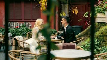 le final baiser de le la mariée et jeune marié dans le café. le jeunes mariés baiser et le concentrer de le caméra se déplace à une vert feuille. video