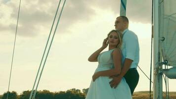 Newlyweds stand on a bow of a sailing yacht like in Titani. The bride put her head on the groom's chest video