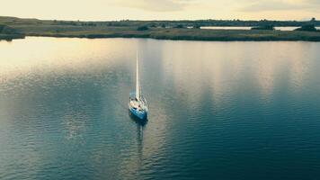 Ukraine. Lemberg. 19.09.2020. einer Yacht im das Meer von ein Vogel Auge Aussicht beim Sonnenuntergang. das Himmel ist reflektiert im das Wasser. Flug beim Sonnenuntergang in der Nähe von das Yacht mit Blick auf das segeln von ein Höhe video