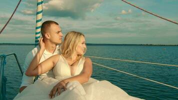 The bride and groom are sitting on a yacht. Looking into the distance at sunset. Beautiful landscape of clouds and lakes video