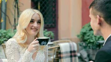 At a street cafe, the bride drinks tea and chats with the groom video