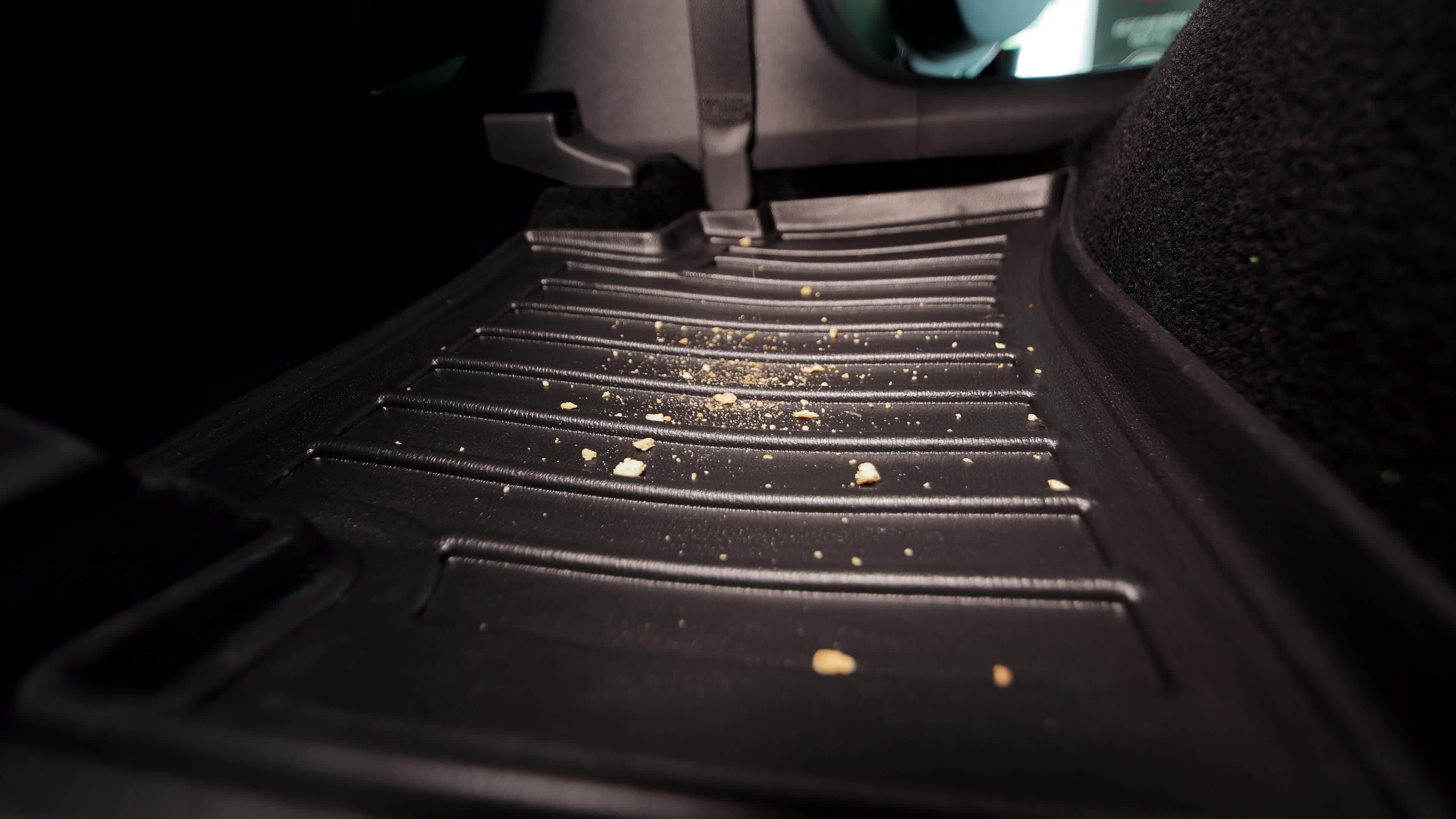 Garbage and dirt in the car. Cookie crumbs fall on the car mat in the