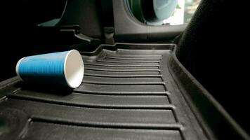 A disposable paper cup falls on the car floor mat in the car. video