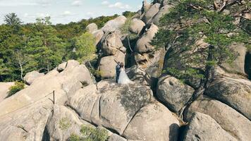 wedding couple in mountain rock from drone. Aerial view Happy newlyweds in love hugging standing on top of the mountain. video