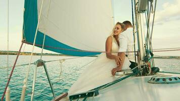 el recién casados son navegación en el lago a bordo el yate. el novia con cerrado golpes el mano de el joven hombre, sonriente video