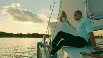 jeunes mariés supporter sur une arc de une voile yacht comme dans titan. le la mariée mettre sa tête sur le du marié poitrine. le jeune marié doucement baisers le la mariée sur le diriger. Regardez à chaque autre video