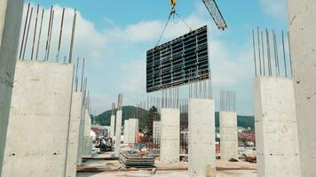 construção do uma multistory prédio, uma guindaste tem levantado uma ampla laje. 2 construção trabalhadores trabalhos em a construção local. a conceito do arranha-céus construção. video