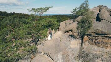 wedding couple in mountain rock from drone. Aerial view Happy newlyweds in love hugging standing on top of the mountain. video