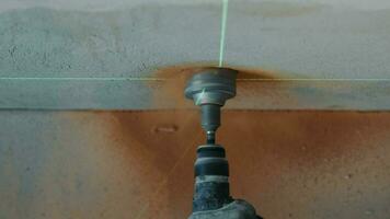 View on top Construction worker drills a hole in the wall under the socket close up. The level of the hole for the electrical outlet is set by a laser. video