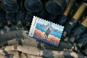 TERNOPIL, UKRAINE - SEPTEMBER 29, 2023 Famous Ukrainian postmark with russian warship and ukrainian soldier as wooden souvenir on army camouflage uniform cloth and machine gun belt photo