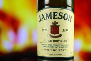 KYIV, UKRAINE - MAY 4, 2022 Jameson original alcohol bottle on wooden table with red fireplace photo