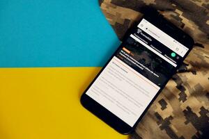 KYIV, UKRAINE - 4 MAY, 2023 Hromadske ukrainian news portal on smartphone screen with ukrainian flag and camouflage fabric photo