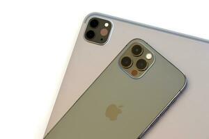 KYIV, UKRAINE - 4 MAY, 2023 Apple brand devices iphone and ipad lies on macbook body photo
