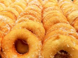 Closeup and crop lots of doughnut with sugar on shelf in the bakery shop background and wallpaper. Doughnut is the one causes disease of Coronary Artery Disease and Obesity. photo