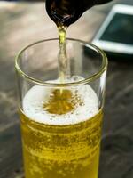 pouring beer into glass on wooden table photo