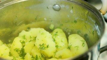 Kaukasisch hand- opent deksel van braadpan met stomende gekookt aardappelen met dille video