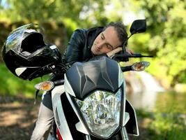 in nature in tranquility, a man fell asleep on a motorcycle, can be used to advertise relaxation on a trip, the photo adjusts to relaxation