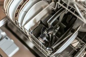 Dishwasher after cleaning process, soft focus closeup of metal silverware. Spoons and plates photo