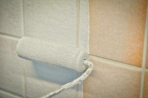 Painting old tiles in the kitchen or bathroom white with a small roller and two component paint. photo