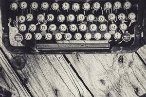 Old and weathered antique typewriter keyboard on wooden background in greyscale. photo
