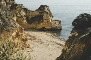Empty and abandoned beach surrounded by cliffs on the coast of Algarve near Lagos. photo