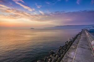 Black sea at a beautiful sunrise, breakwater and ship in the light of the rising sun, Varna, Bulgaria photo