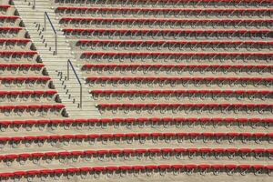 Empty red plastic chairs in the stands of the stadium or amphitheater. Many empty seats for spectators in the stands. photo